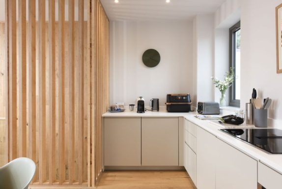 Modern kitchen featuring wooden partition, appliances, and minimalistic design.